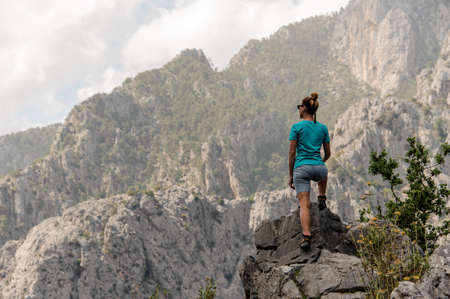 Rear view sporty woman standing on the rock on the beautiful landscapeの写真素材