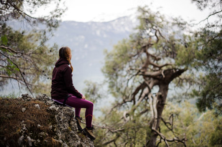 Female tourist sits on a cliff in forest