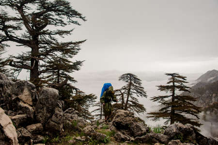 Female traveller in raincoat hikes at topの写真素材
