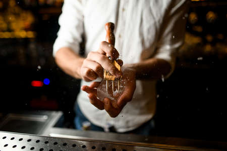 Male bartender crushing ice cube with a special instrumentの写真素材
