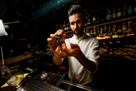 Fish-eye shot bartender crushing ice cube with a special instrumentの写真素材