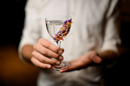 Barman presenting a cocktail in the glass decorated with flowersの写真素材