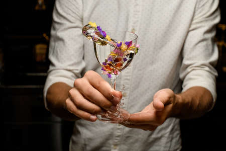 Bartender making a splash with a cocktail in the glass decorated with flowersの写真素材