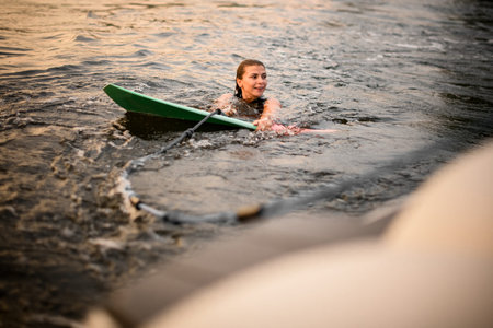 Girl swimming holding the wakeboard and a rope of the motorboat