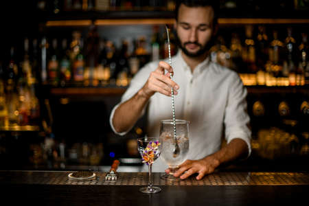 Bartender stirs an alcohol cocktail with bar spoonの写真素材