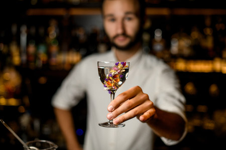 Bartender with beard holds alcohol in glass