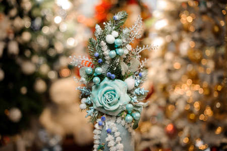 Vase with christmas decor composition of blue flowers, toys, fir-tree branches in the blurred background of winter decorationの写真素材