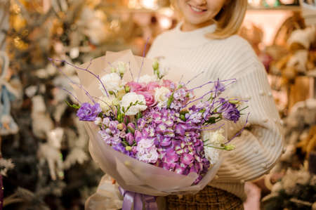 Girl holding a bouquet with pink, purple and white flowers wrapped in matte transparent paperの写真素材