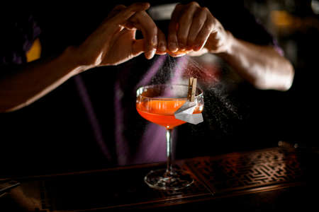 Bartender spraying on the cocktail decorated with paper airplane in the clothespin with a orange zest juiceの写真素材