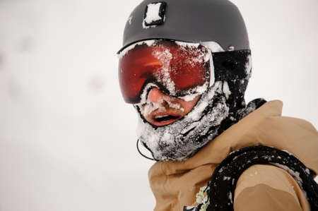 Snowboarder standing on the slope in the protective glasses looking at the cameraの写真素材
