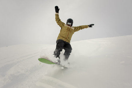 Snowboarder riding down the hill holding hands up