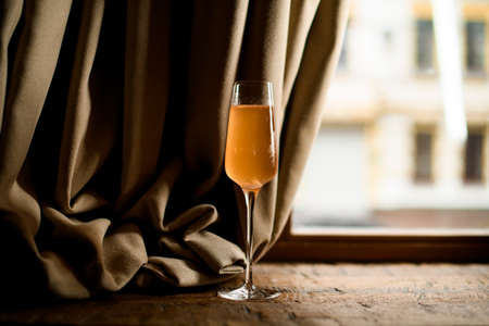 Delicious yellow alcoholic cocktail in the tall champagne glass on the tableの写真素材