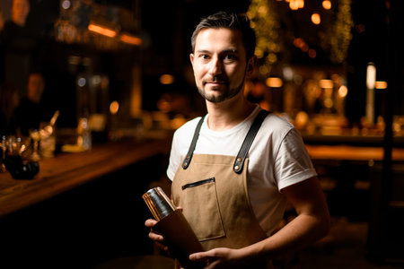 Portrait of bartender in apron and t-shirt with shaker