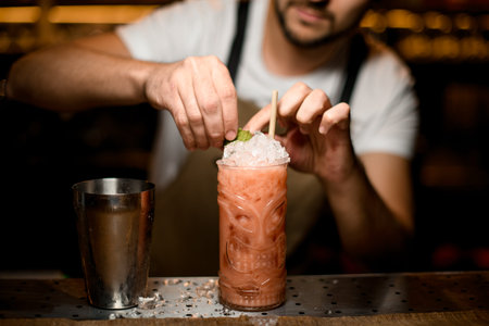 Bartender decorates cocktail with a mint leaf