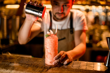 Bartender sprinkles an alcohol drink with spices