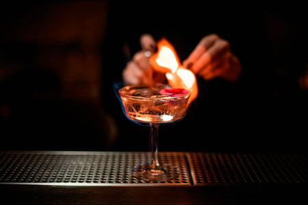 Woman bartender serving on fire alcoholic transparent cocktail with ice in the glass decorated with...