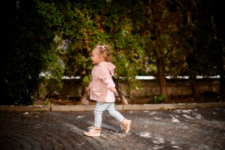 Smiling little girl running in the park on the paving stones