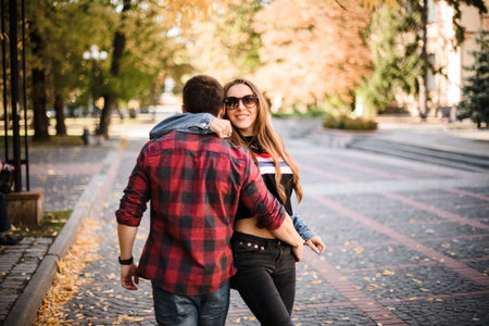 Romantic couple walking in the autumn park and man hugging woman