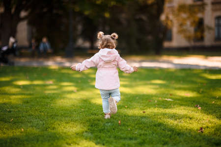 Cute little girl running in the park on the green grassの写真素材