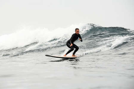 Woman in the black diving suit riding on the surfing board on the bending kneesの写真素材