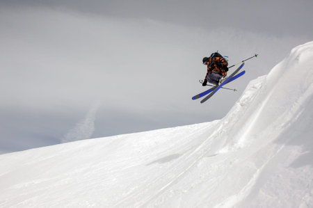 Brave skier takes off the ground while sliding down the snowy mountains
