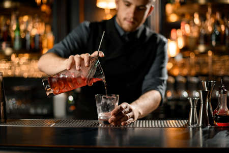 Close-up of bartender pouring cocktail from strainerの写真素材