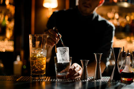 Bartender putting precisely ice cube in cocktail glassの写真素材