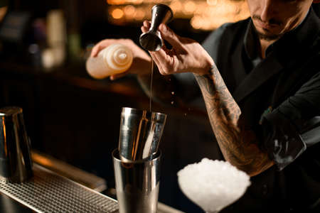 Bartender pouring syrup from jigger to shakerの写真素材