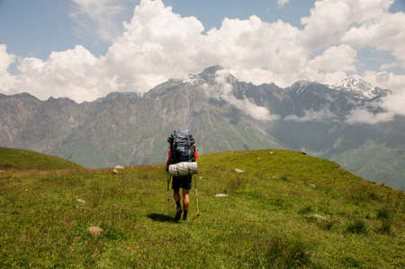 Hiker with backpack walks among hills and mountainsの写真素材