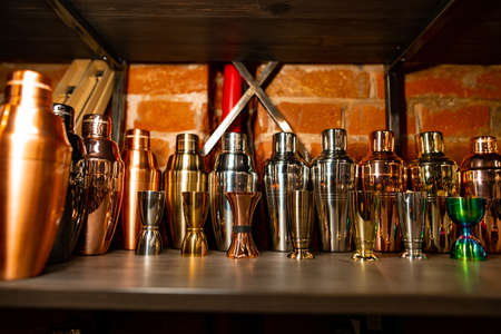 Professional bartender equipment as different metal color jiggers and shakers on the shelf in the barの写真素材