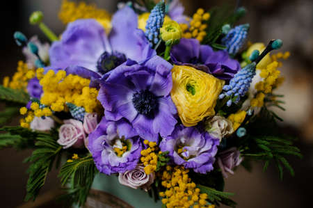 Box full of purple tender color flowers and yellow mimosa decorated with green leaves in the background of flower shopの写真素材