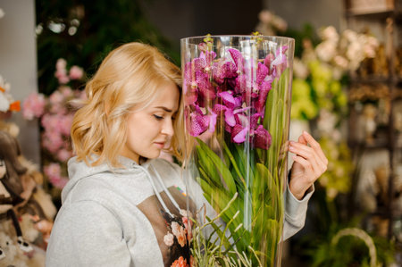 Girl holding a beautiful pink orchid with green leaves in a pot in the wrapping paper