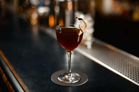 Brown cocktail in the glass decorated with a dried leaf by a pinの写真素材