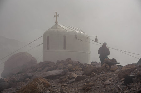 Old christian church standing among mountains in fog