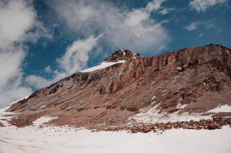 Smooth mountain slope covered in snow under cloudy sky