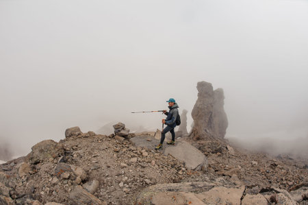 Man standing on the rocky mountain hill under the white fog on the way on meteostation in Kazbek,...
