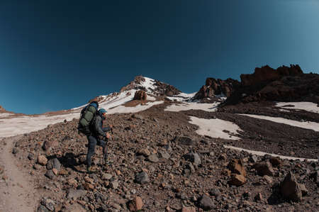 Man standing on the rocky path looking up to the mountainの写真素材