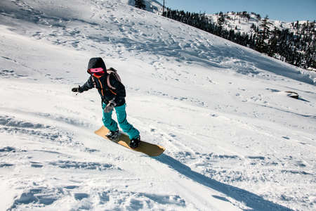Woman freeriding from mountain on a professional snowboardの写真素材