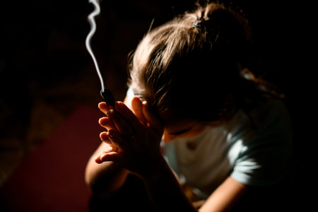 Woman in sport clothes practicing yoga in a studio room hold hands in namaste holding a palo santoの写真素材
