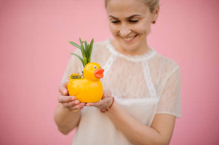 Girl holding a flower pot in the shape of duck with the yellow narcissus with green leavesの写真素材