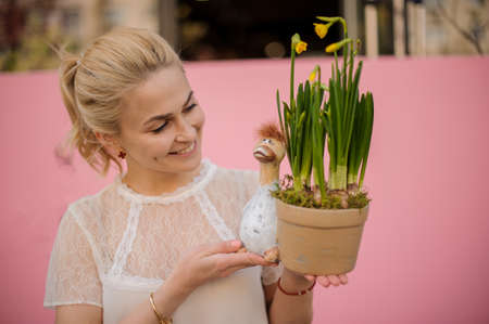 Girl holding a flower pot with a ceramic duck with the yellow narcissus with green leavesの写真素材