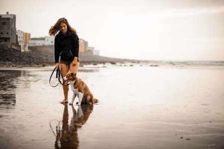 Girl standing with her cute dog on the sea coastの写真素材