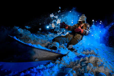 GIrl snowboarder slides on a snowboard in nightの写真素材