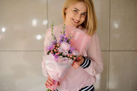 Young blond woman holding big beautiful blossoming bouquetの写真素材