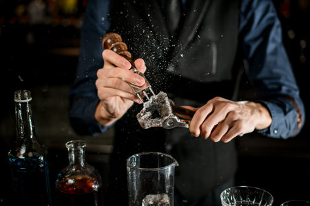 Bartender breaks the ice for a cocktail and the pieces fly apart.