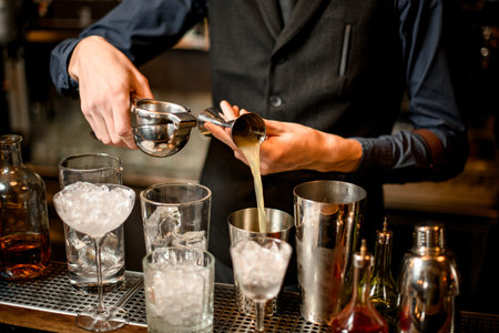 bartender pours squeezed juice from a beaker into a shaker