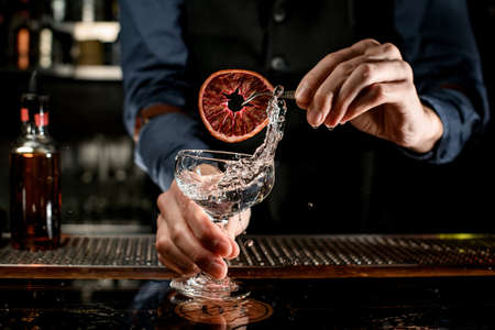 splashing drink in glass decorated with slice of citrus by barmanの写真素材
