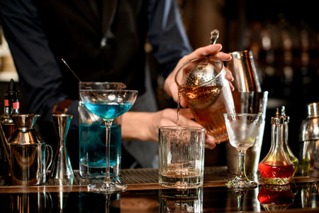 Barman pours a cocktail from one glass to another.