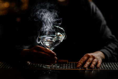 woman bartender holds glass with white transparent splashing drink.の写真素材