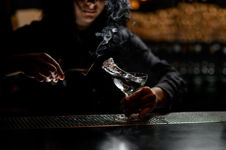 bartender girl holds smoking wand and glass with white splashing drink.